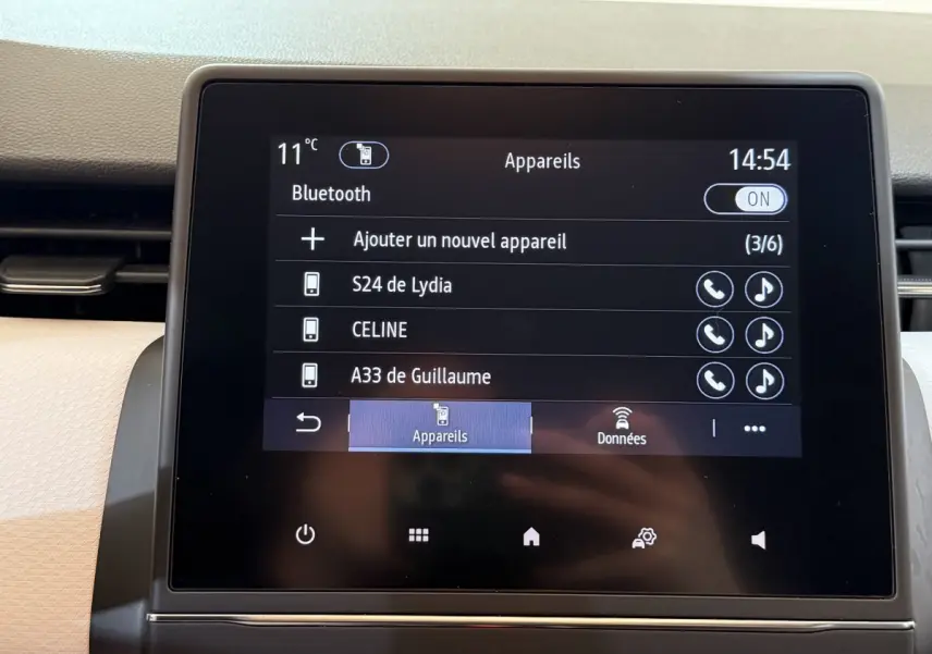 Écran tactile central affichant la connexion Bluetooth dans l’habitacle clair d’une Renault Clio blanche.