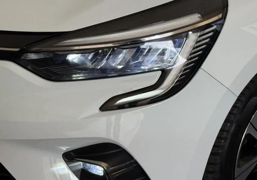 Gros plan sur le phare avant droit blanc de la Renault Clio Business TCe 100 GPL avec feu LED et partie de la roue visible.