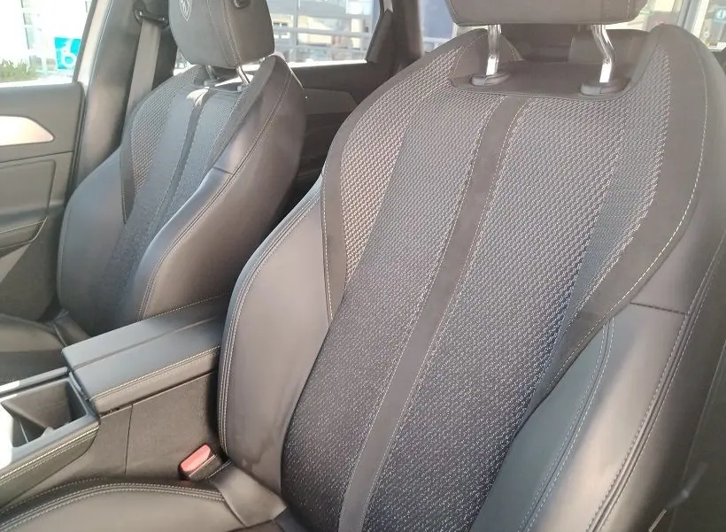 Gros plan sur les sièges avant en cuir et tissu noir de la Peugeot 308 SW Hybrid 145 GT, intérieur moderne et soigné.