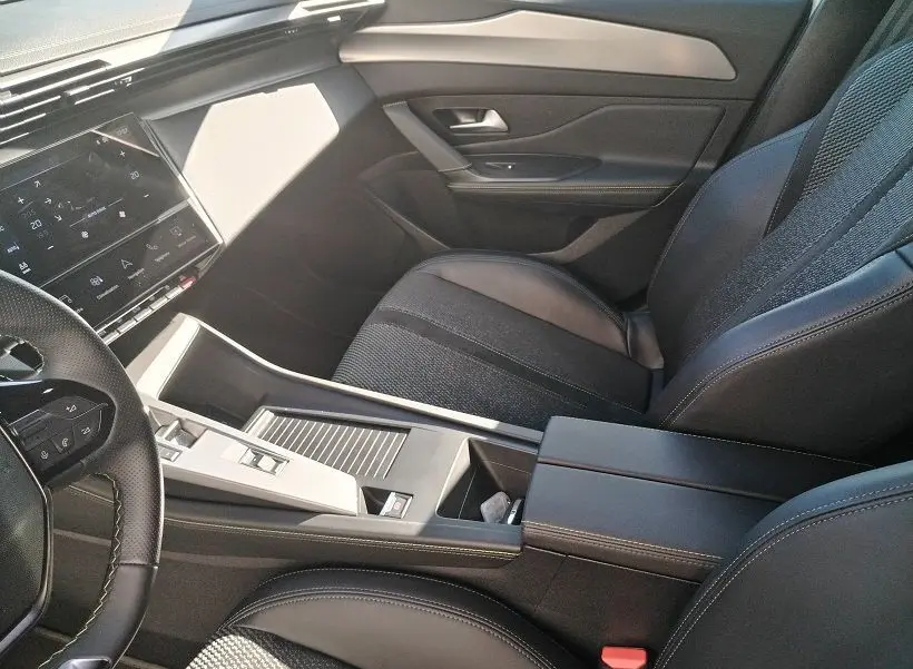Intérieur de la Peugeot 308 SW Hybrid 145 GT, vue côté passager, sièges noirs et console centrale moderne.
