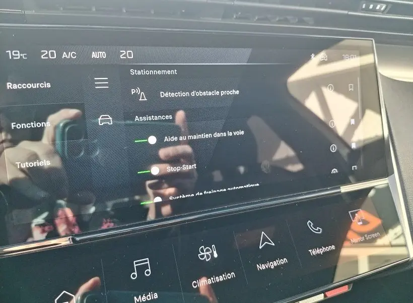 Écran tactile central de la Peugeot 308 SW Hybrid 145 GT montrant les options d’aides à la conduite et climatisation.