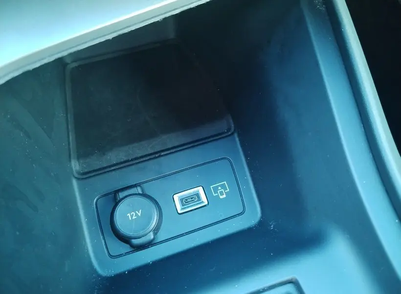 Gros plan sur la console centrale noire du Peugeot 308 SW Hybrid 2025, montrant prise 12V et port USB.