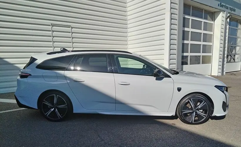 Peugeot 308 SW Hybrid 145 GT blanc Okenite vue de profil côté gauche, avec jantes noires et toit panoramique.
