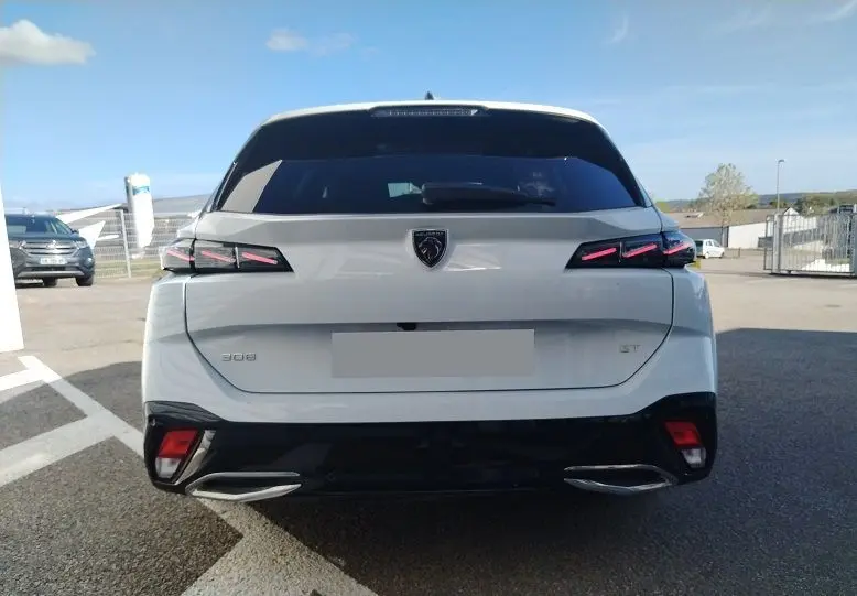 Vue arrière d'une Peugeot 308 SW Hybrid 145 GT blanche Okenite avec feux arrière LED distinctifs et double sortie d'échappement.
