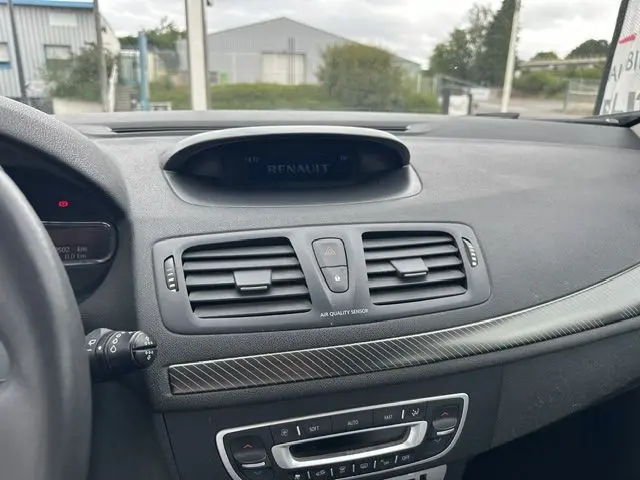 Tableau de bord intérieur de Renault Mégane 3 gris, vue centrée sur les aérateurs et commandes de climatisation.