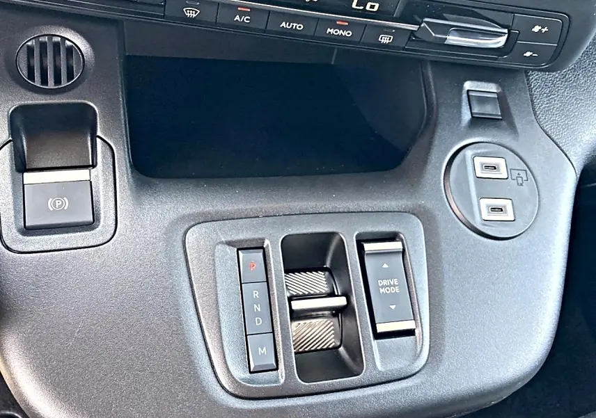 Gros plan sur la console centrale noire du Citroën Berlingo 2026 avec commandes de boîte auto et prises USB.