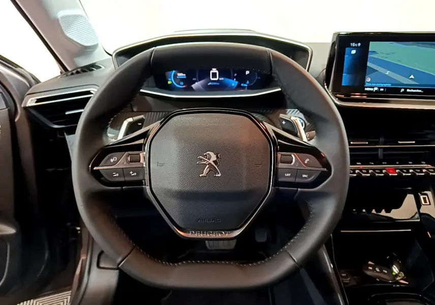 Volant cuir noir avec logo Peugeot au centre, tableau de bord numérique et écran tactile à droite dans l'habitacle d'une 208 2022.