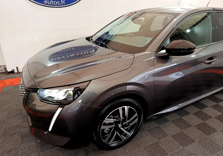 PEUGEOT 208 gris foncé en vue 3/4 avant droit, mettant en valeur ses phares LED et jantes alliage modernes.