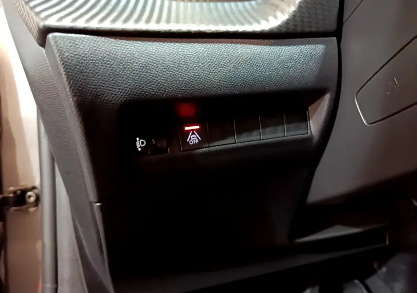 Gros plan sur les commandes côté gauche du tableau de bord gris foncé d'une Peugeot 208 2022, avec bouton d'assistance désactivée.