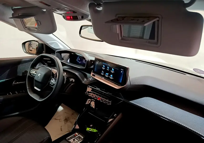 Vue intérieure côté conducteur du tableau de bord de la Peugeot 208 2022 avec écran tactile et volant cuir multifonction.