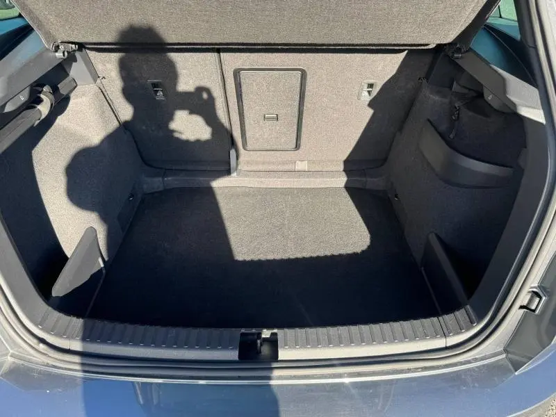 Coffre ouvert vu de l'arrière d'un Skoda Karoq gris, montrant un espace de chargement propre et bien fini.