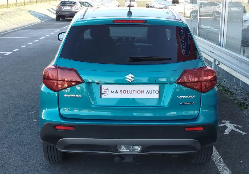 Vue arrière d'un Suzuki Vitara 2023 hybride en turquoise métallisé, avec logo et feux arrière distinctifs visibles.