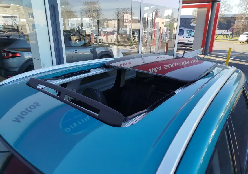 Toit ouvrant panoramique ouvert vu en plongée sur un Suzuki Vitara 2023 turquoise métallisé.