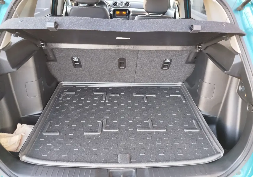 Vue arrière du coffre ouvert du Suzuki Vitara 2023 en turquoise Atlantis, avec tapis de protection noir et intérieur gris.
