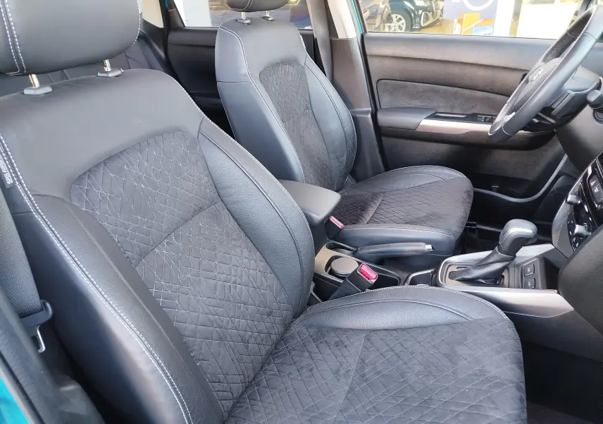 Vue intérieure côté avant droit du Suzuki Vitara 2023, sièges en cuir et alcantara gris foncé avec surpiqûres blanches.