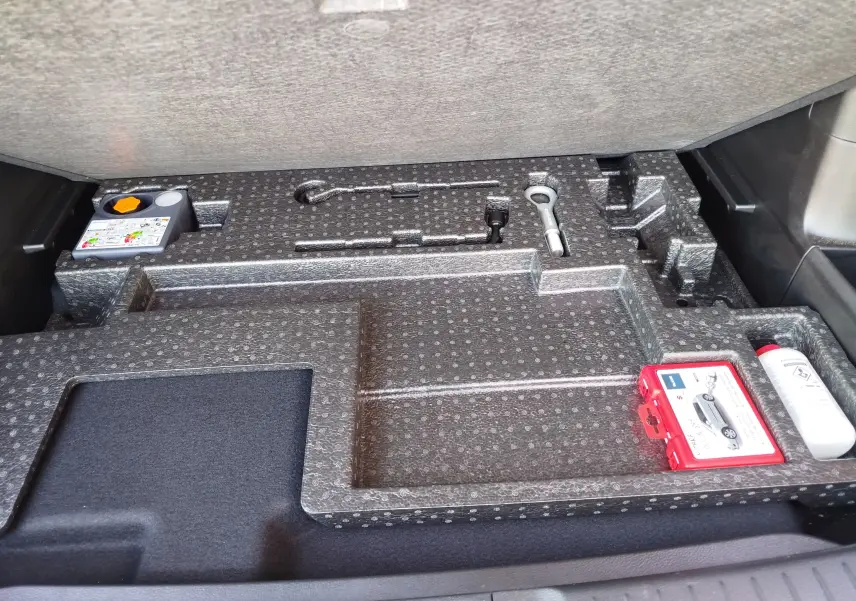 Vue du compartiment de rangement sous le plancher du coffre du Suzuki Vitara 2023, avec kit de réparation pneus et outils intégrés.