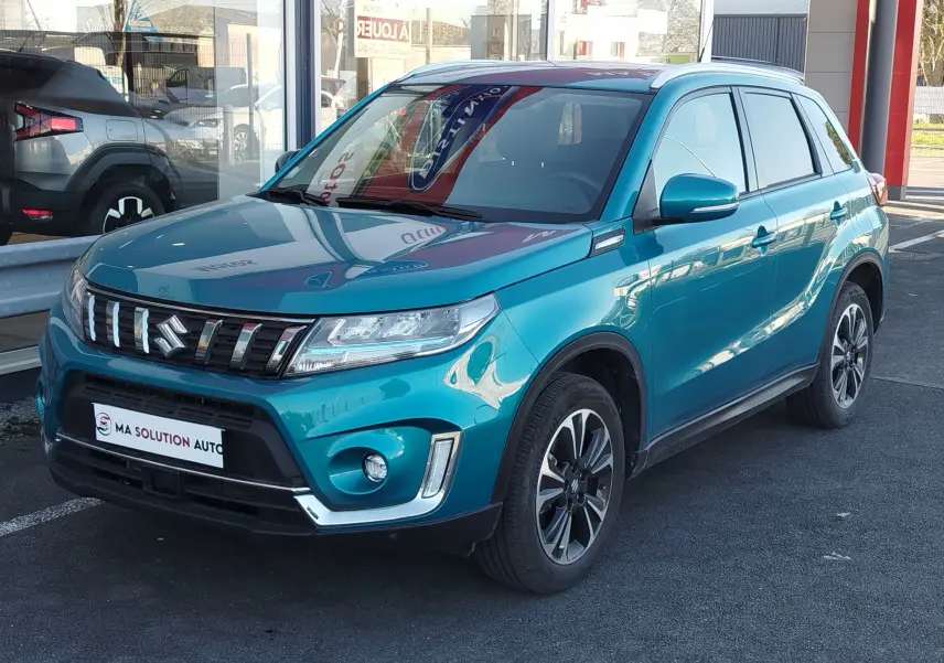 Suzuki Vitara 1.5 Hybrid 2023 en turquoise atlantis, vue 3/4 avant droit avec jantes bi-ton et calandre distinctive.