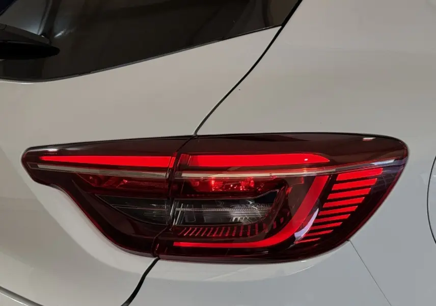 Gros plan sur le feu arrière droit rouge d’une Renault Clio Business blanc nacré, soulignant ses lignes modernes.