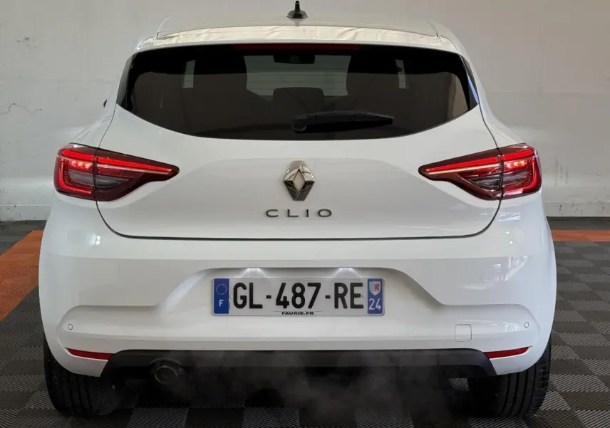 Vue arrière d'une Renault Clio blanche 2023 avec feux LED allumés et plaque d'immatriculation française visible.