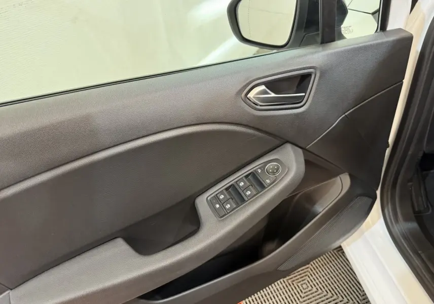 Vue rapprochée de la porte avant gauche blanche d’une Renault Clio 2023 avec commandes électriques des vitres et rétroviseur.
