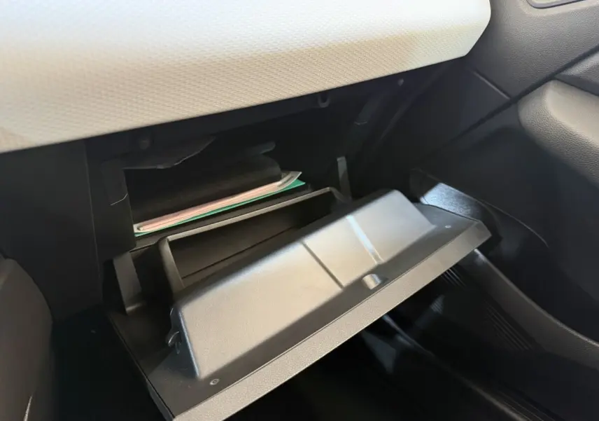 Gros plan sur la boîte à gants ouverte de la Renault Clio Business blanche, montrant l'intérieur et la planche de bord claire.