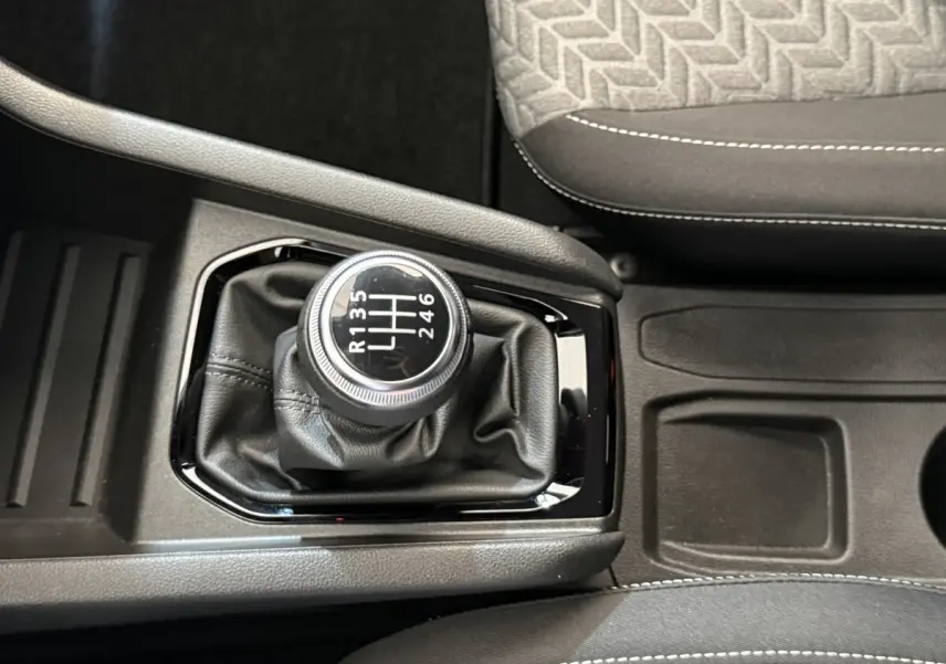 Gros plan sur levier de vitesses manuel noir dans Renault Clio Business blanc, avec sellerie grise et console centrale.