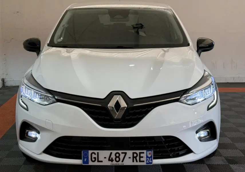 Vue avant d'une Renault Clio Business TCe 100 GPL blanche avec phares LED allumés et calandre noire distinctive.