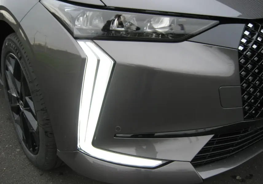 Gros plan sur le phare avant gauche et la signature lumineuse en forme de flèche du DS4 gris platinium 2024.
