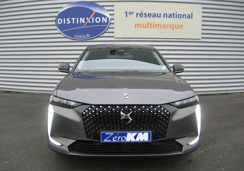 Vue frontale d'une DS4 2024 gris platinium avec calandre noire à motif losange et feux LED verticaux allumés.