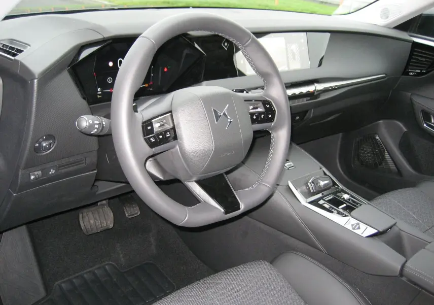 Intérieur du DS4 2024 en gris, vue côté conducteur sur le volant cuir et la console centrale moderne avec écran tactile.