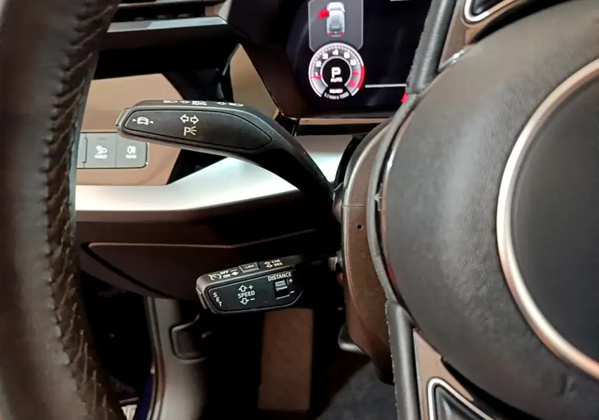 Gros plan sur le volant noir et les commandes au volant côté gauche de l'Audi A3 35 TFSI 2023 avec affichage numérique.