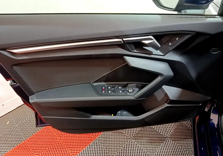 Porte avant gauche ouverte de l'Audi A3 35 TFSI bleu 2023, avec commandes des vitres et verrouillage visibles.