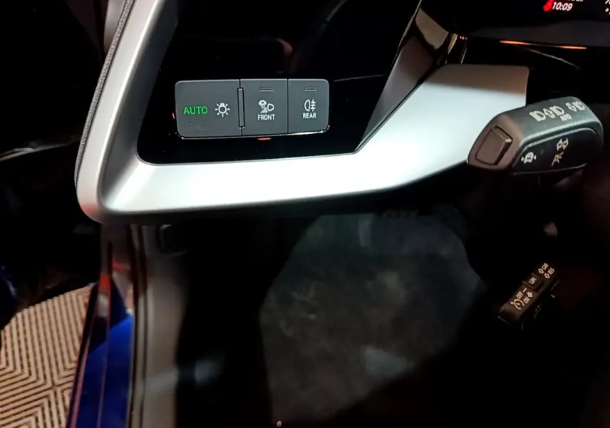 Détail du tableau de bord argenté avec commandes d'éclairage et leviers de fonction dans l'Audi A3 bleu 2023.