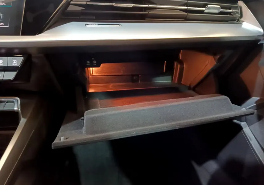 Vue rapprochée de la boîte à gants ouverte de l'Audi A3 35 TFSI Business Line, éclairage intérieur visible.