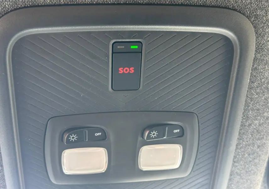 Vue en gros plan du plafonnier intérieur noir avec bouton SOS rouge et commandes d'éclairage du Dacia Duster 2026.