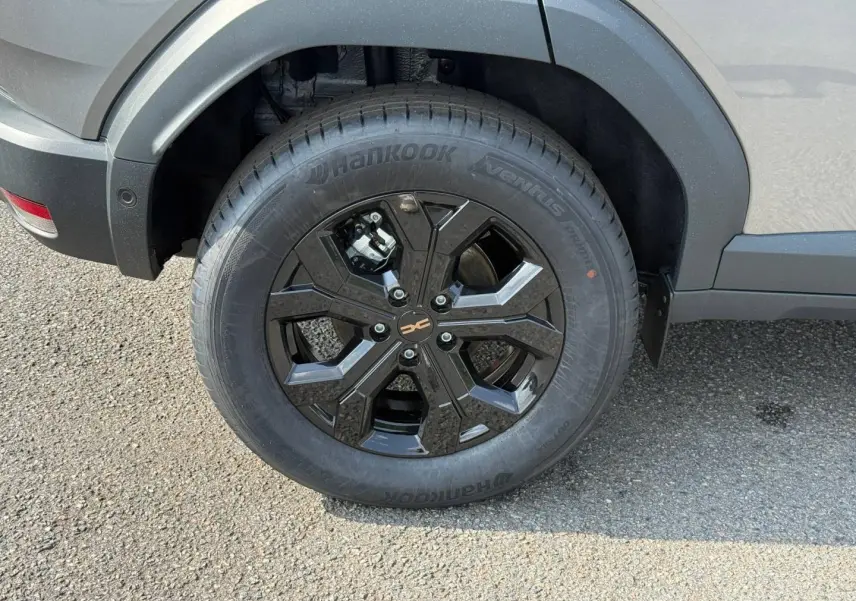 Gros plan sur la roue arrière droite du Dacia Duster gris 2026 avec jante alu noire et pneu Hankook.