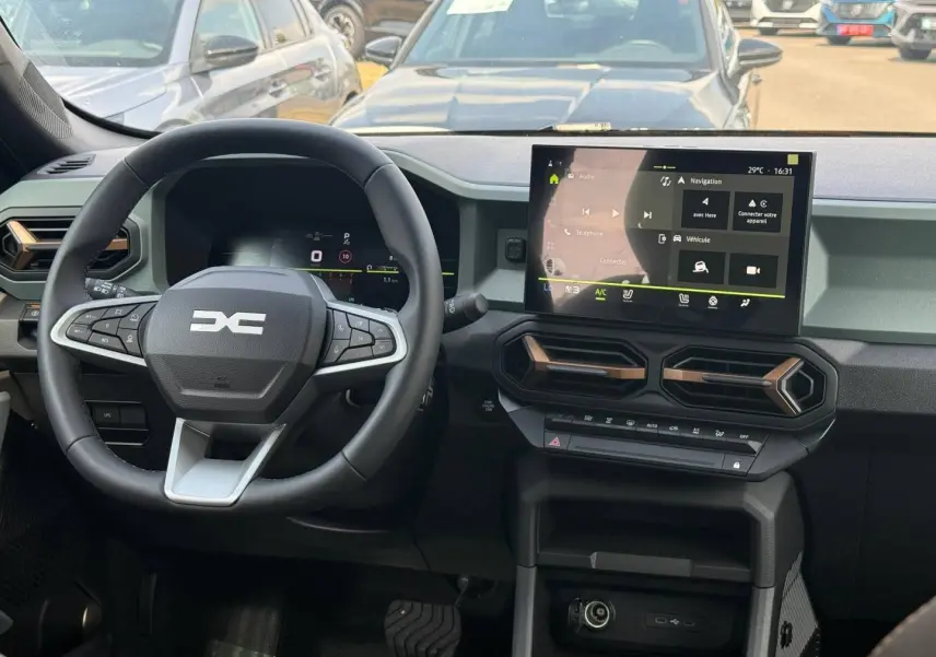 Vue intérieure du tableau de bord du Dacia Duster 2026 avec écran tactile et volant multifonction noir.