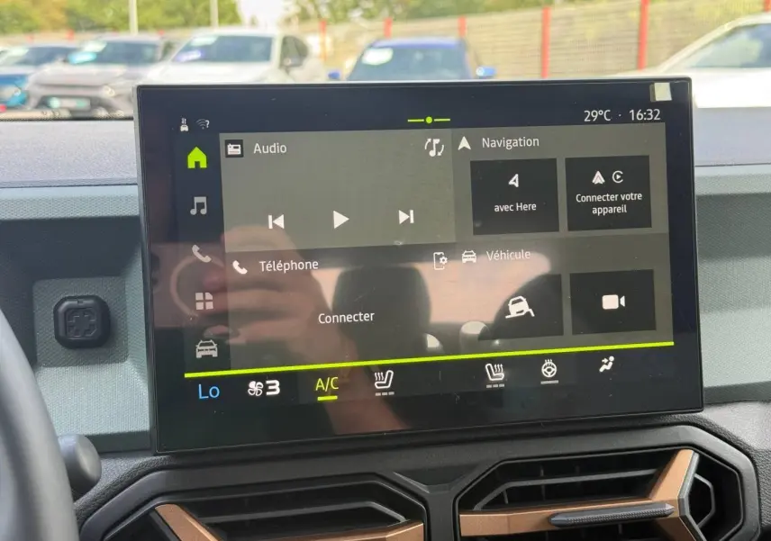 Écran tactile central du tableau de bord du Dacia Duster gris 2026, affichant les options audio et navigation.