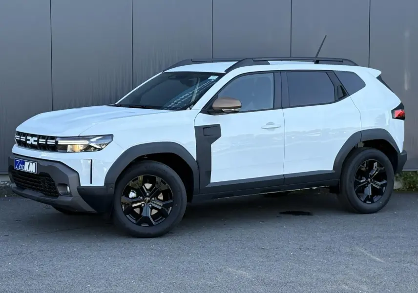 Dacia Duster ECO-G 120 Auto Extrême blanc glacier en vue 3/4 avant droit avec jantes noires et barres de toit.