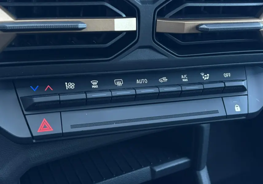 Détail des commandes de climatisation et sécurité du tableau de bord noir du Dacia Duster Blanc Glacier 2026.