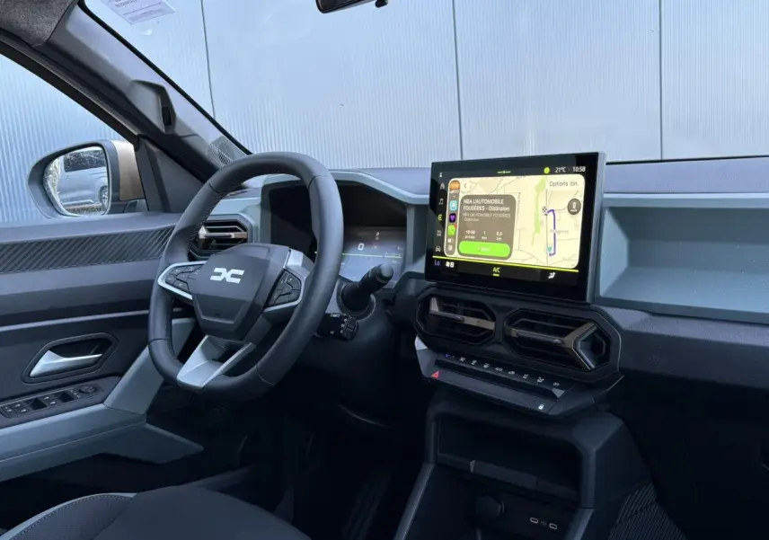 Vue intérieure côté conducteur du Dacia Duster 2026 blanc Glacier, avec tableau de bord digital et écran tactile central.