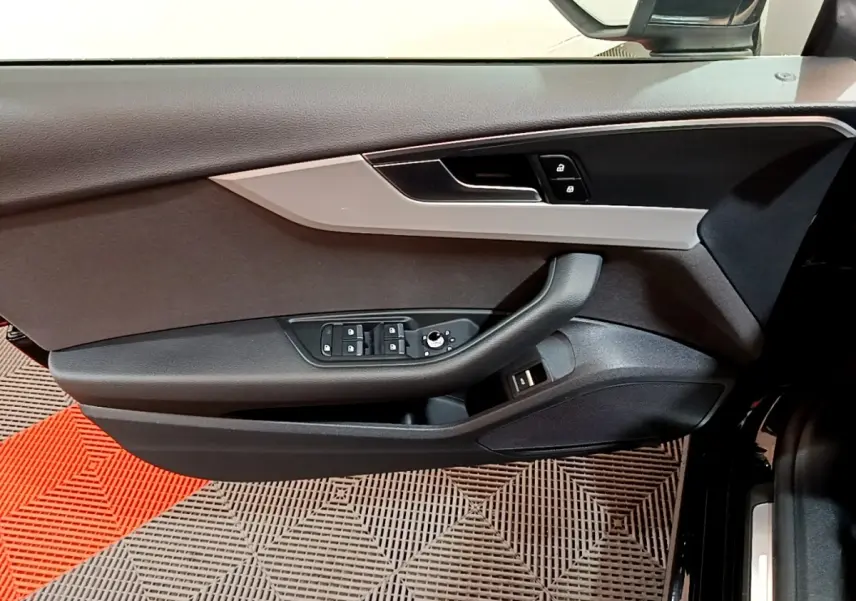 Vue rapprochée de la porte côté gauche d'une Audi A5 noire, avec commandes de vitres et verrouillage intégrés.