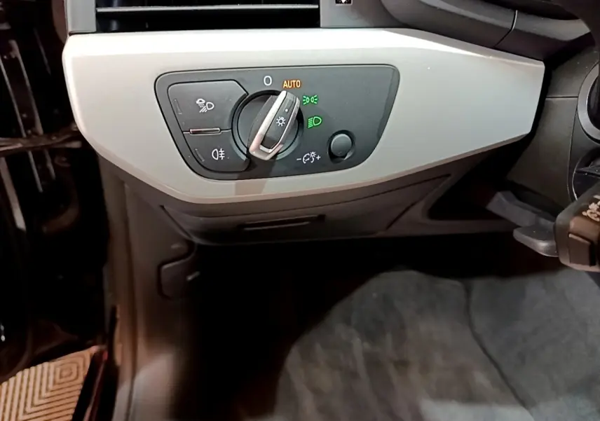 Gros plan sur le panneau de commande des phares à gauche du volant dans l'Audi A5 35 TFSI noire de 2021.