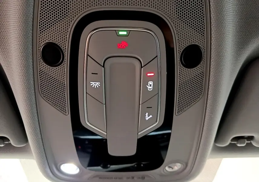 Vue en gros plan du panneau de commandes au plafond intérieur de l'Audi A5 noir, avec bouton SOS et éclairage intégré.