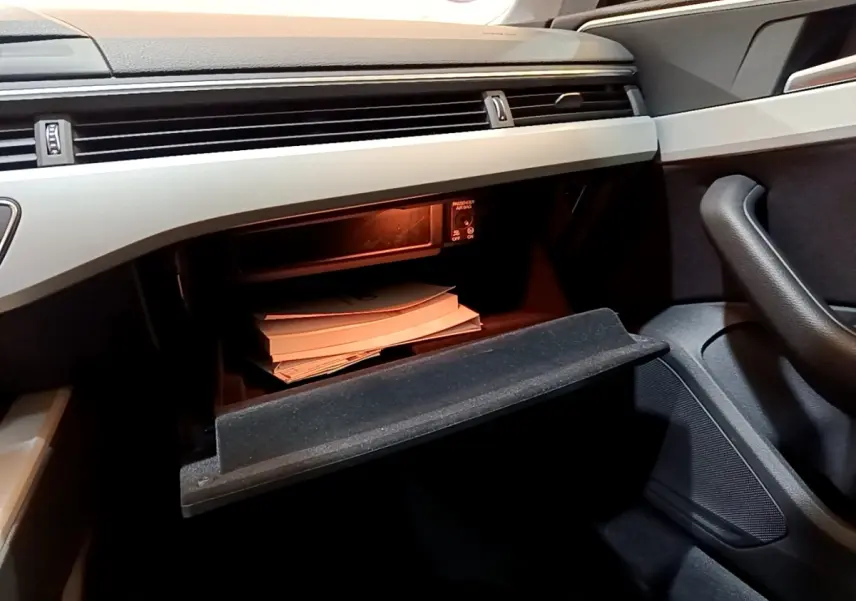 Intérieur de l'Audi A5 35 TFSI 2021, vue du côté passager sur la boîte à gants ouverte avec documents visibles.