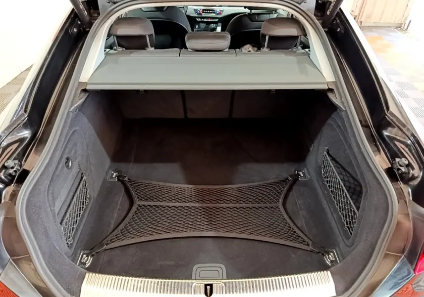 Coffre ouvert noir d'Audi A5 35 TFSI 2021 avec filet de rangement et tablette de séparation visible depuis l'arrière.