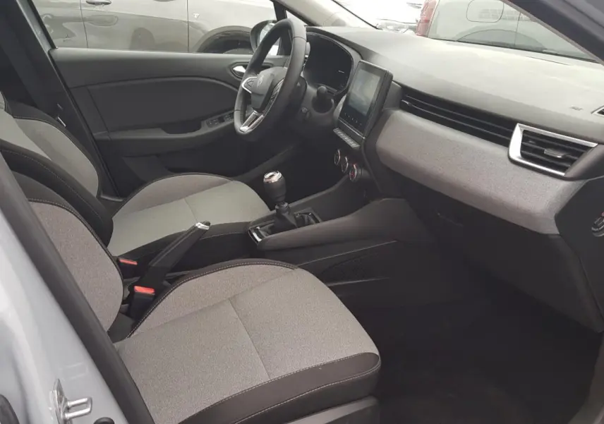 Vue intérieure côté conducteur de la Renault Clio gris 2025, montrant sièges tissu bicolore et tableau de bord moderne.