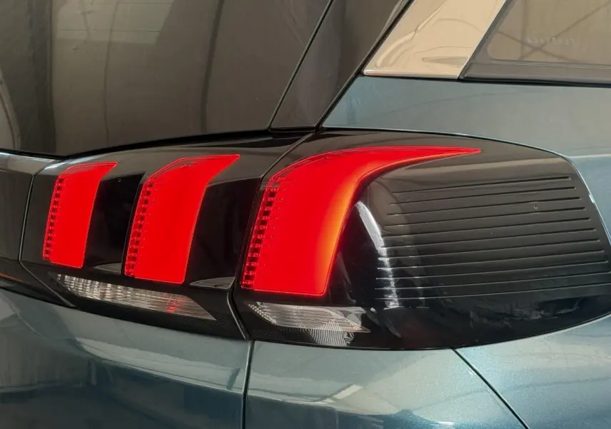 Gros plan sur le feu arrière droit rouge et noir du Peugeot 5008 bleu, soulignant ses lignes modernes et anguleuses.
