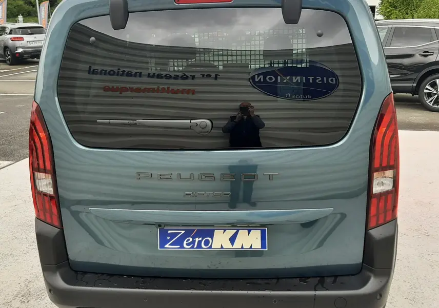 Vue arrière d'un Peugeot Rifter bleu Kiama 2026 avec hayon vitré et feux arrière verticaux rouges.