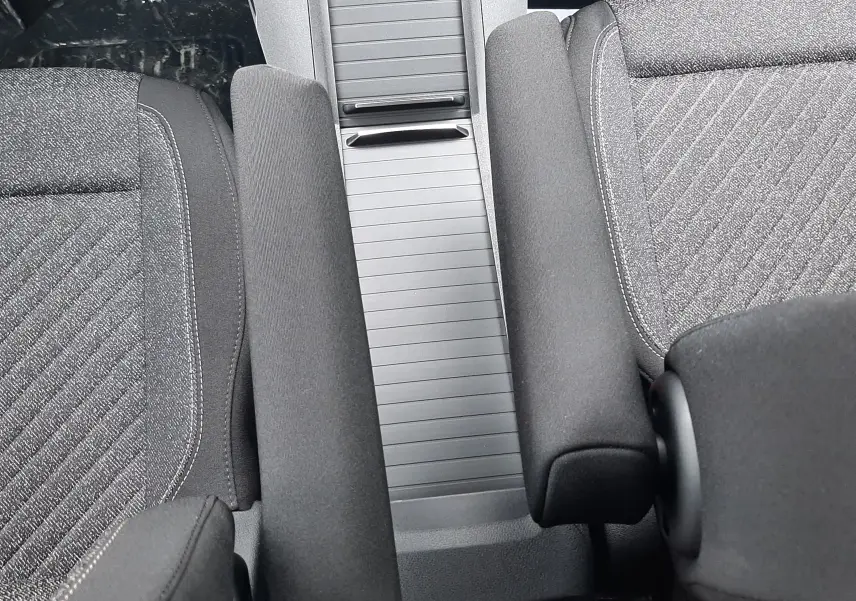 Vue intérieure rapprochée du Peugeot Rifter 2026 montrant la console centrale et les accoudoirs en tissu gris.